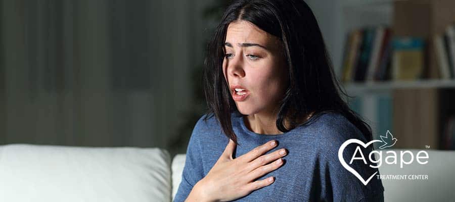 woman grabbing her chest experiencing the panic stage of anxiety