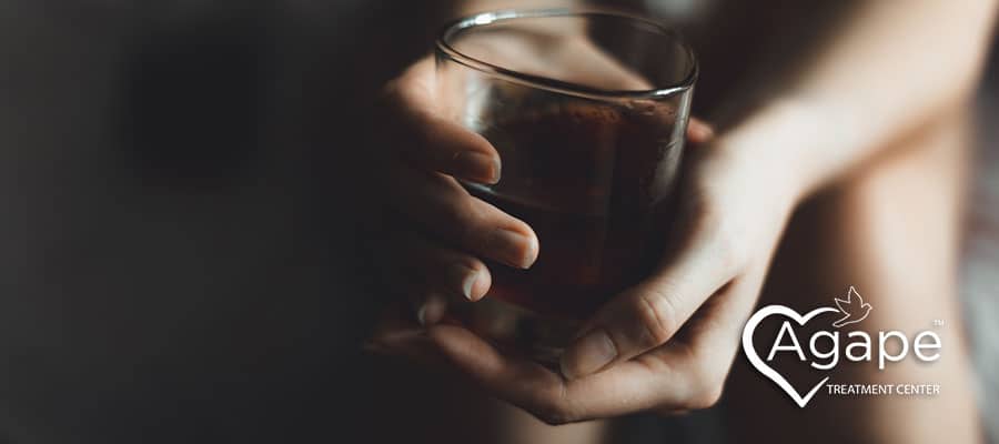 close-up image of a woman holding a glass of dark liquor