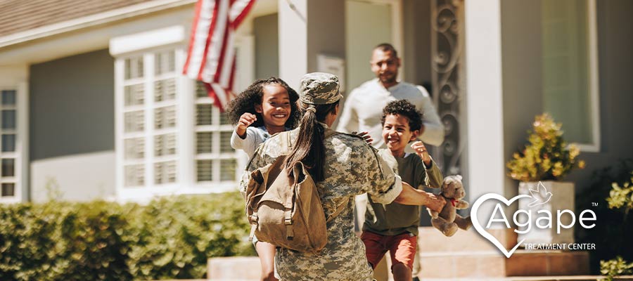 female service member greets her children and husband outside of their home after being deployed