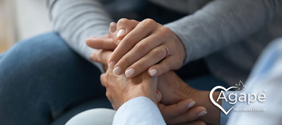 two loved ones supporting each other holding handing while sitting